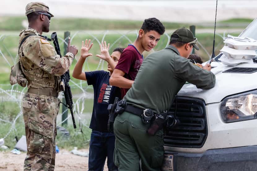 Un niño explica con sus manos a un agente de la Guardia Nacional que él tiene 10 años,...