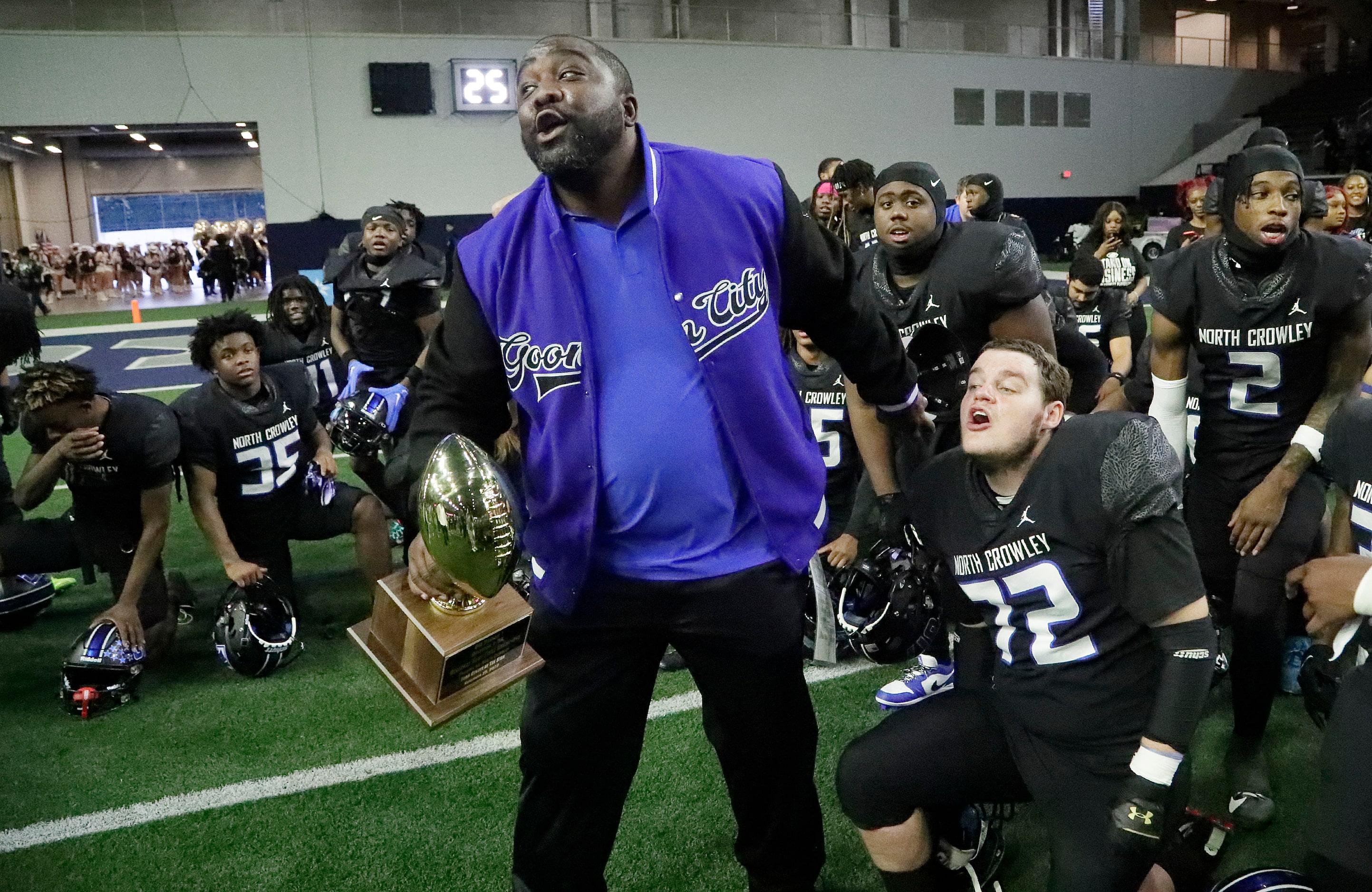 North Crowley High School head coach Ray Gates holds the trophy next to North Crowley High...