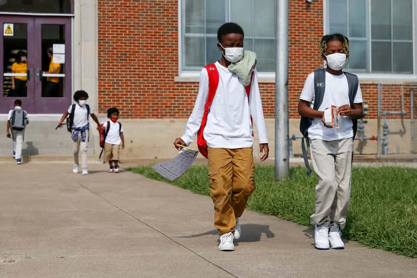 Jerrell Brown (left), 9, walks with Jayce Williams, 7, after a day of classes at Paul L....