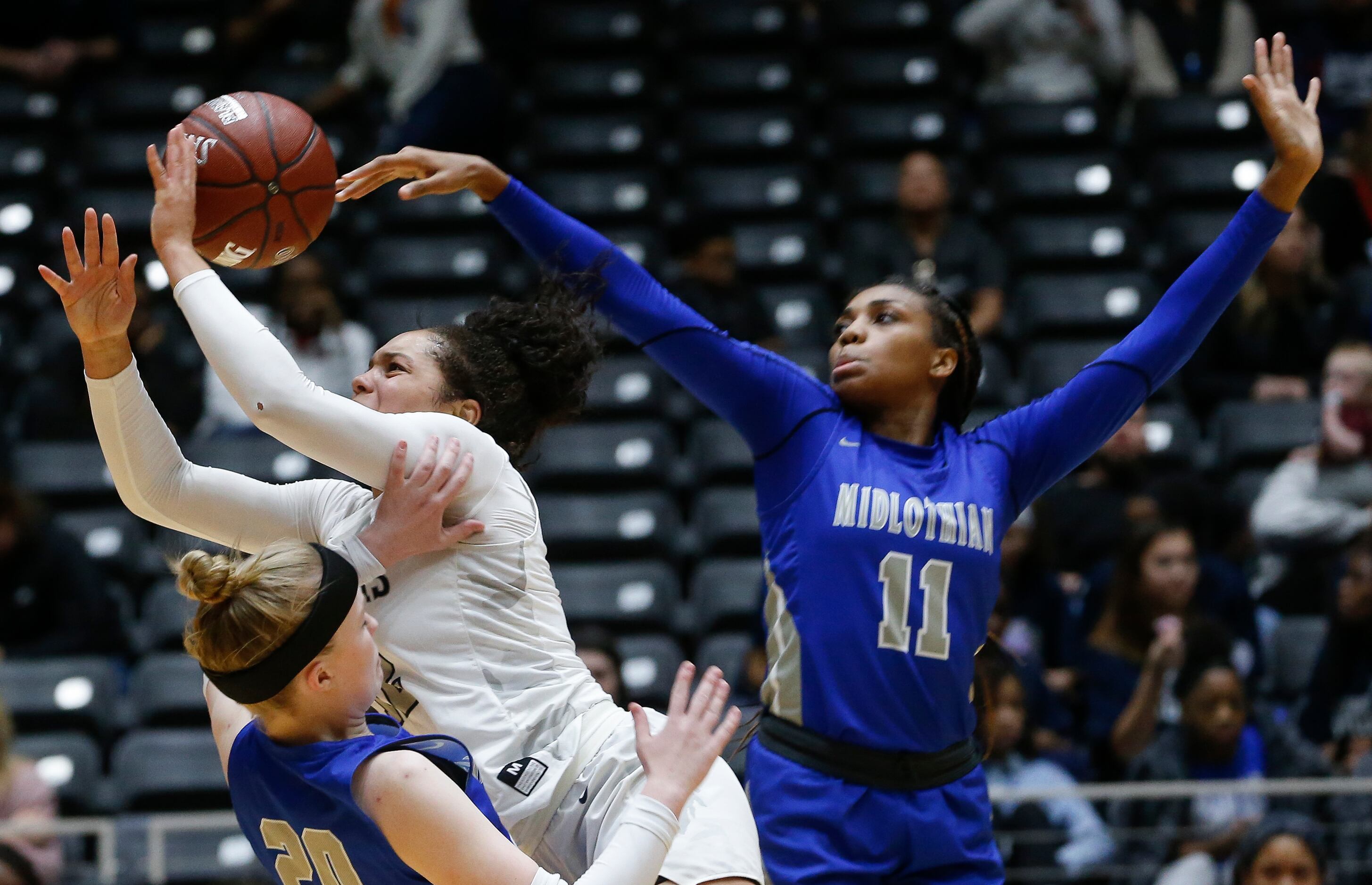 Frisco Lone Star's Kyla Deck (12) goes up for a shot over Midlothian's Hallie Mayfield (20)...
