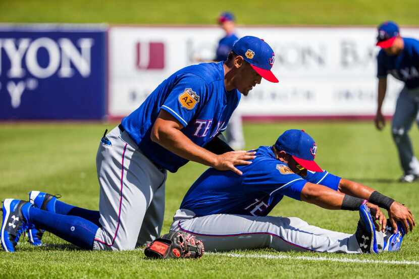 Texas Rangers first baseman Ronald Guzman (67) helps catcher Jose Trevino (71) stretch...