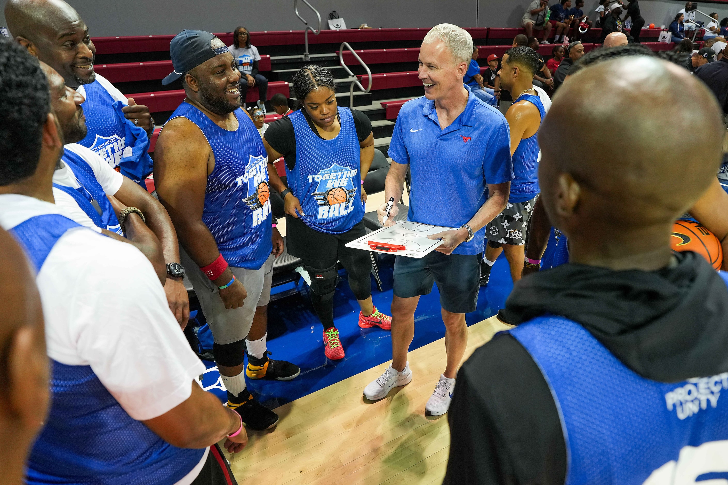 The blue team gathers around SMU men’s basketball coach Andy Enfield before the 8th Annual...