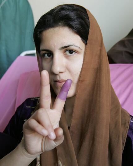 An Iraqi woman shows her finger marked with ink after voting at a Baghdad hospital in...