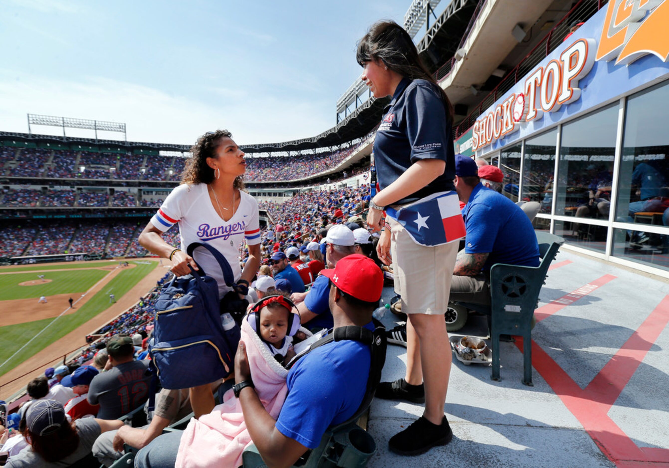 Texas Rangers usher Margarita Aguirre (right) helps fans Nikki Pugh and her husband Jordan...