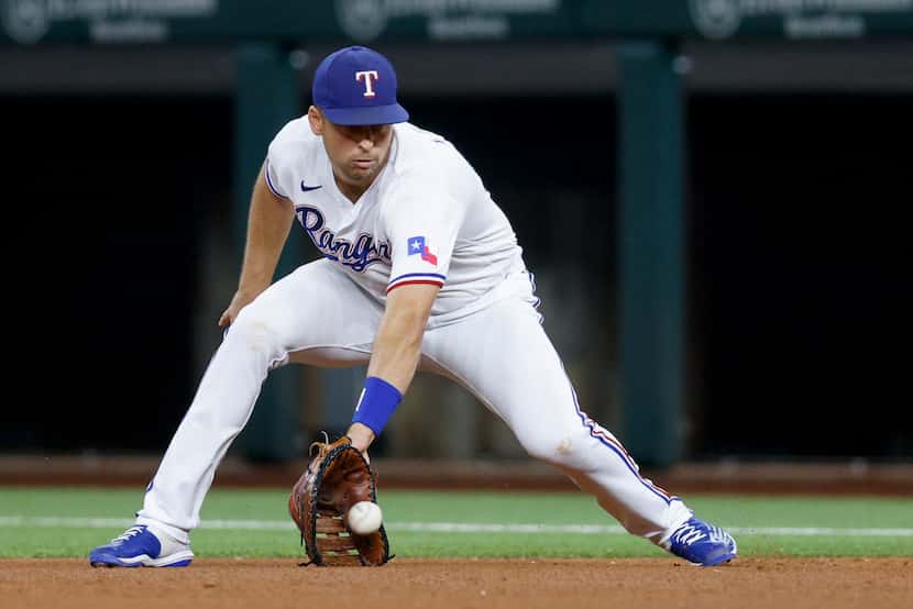 Texas Rangers first baseman Nathaniel Lowe (30) fields the ball before throwing to first...