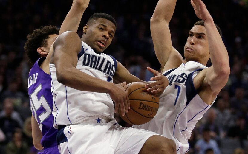 Dallas Mavericks guard Dennis Smith Jr., center, grabs a rebound between Sacramento Kings...