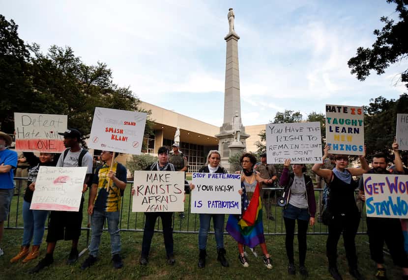 Protestors line the fence surrounding the Confederate War Memorial in Pioneer Park chanting...
