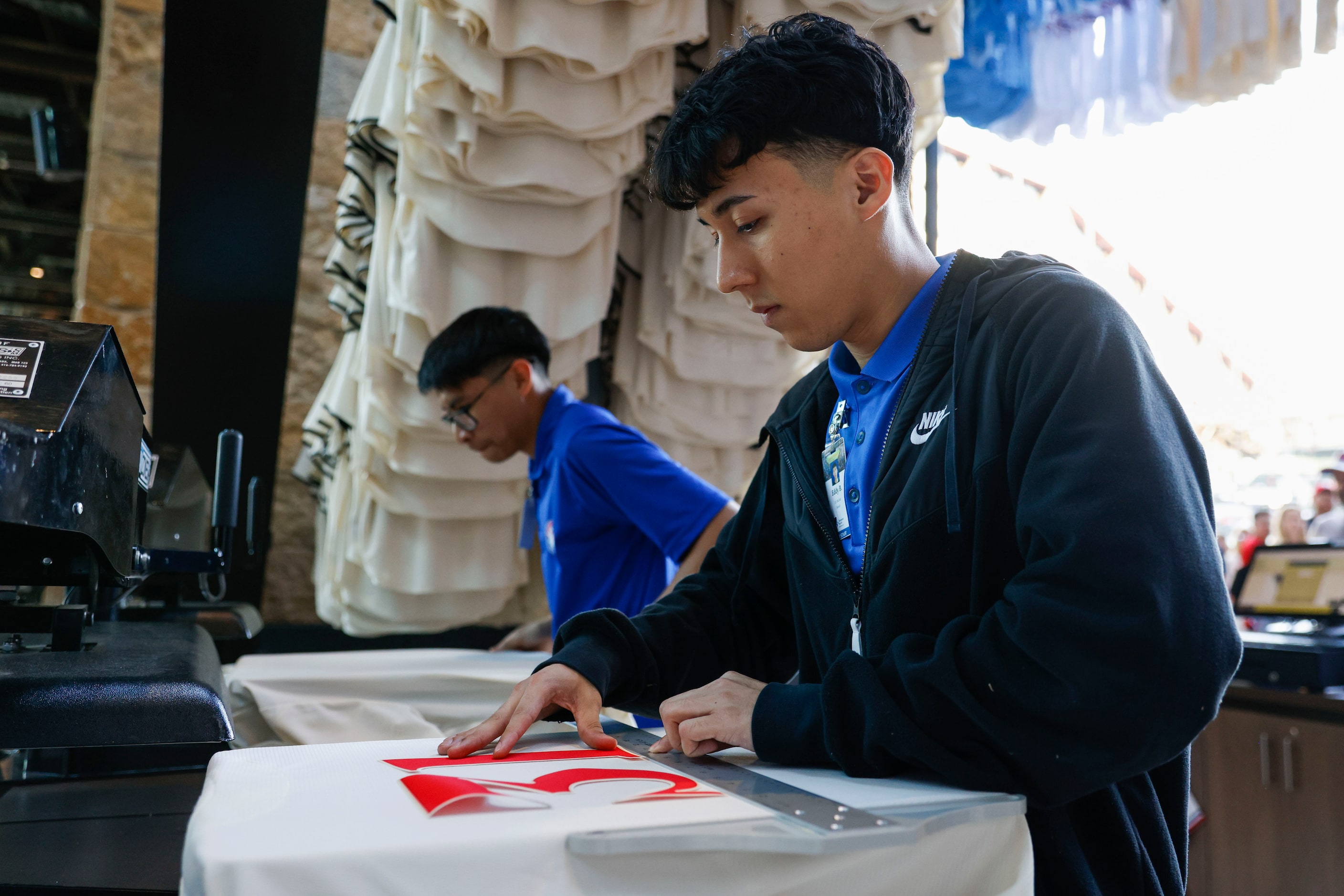 Eddy Briseno prepares a Texas Rangers City Connect jersey for a customer before a baseball...