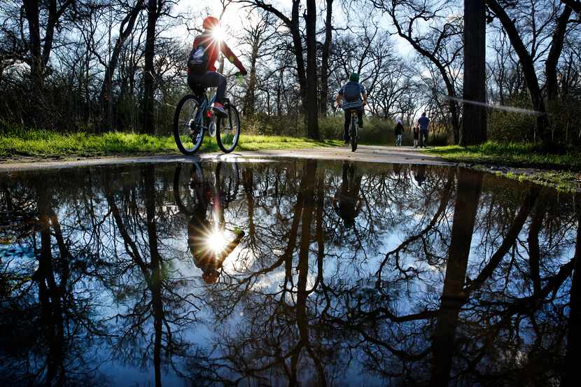 After overnight rains, cyclists and walkers navigate the water puddles along the paths of...