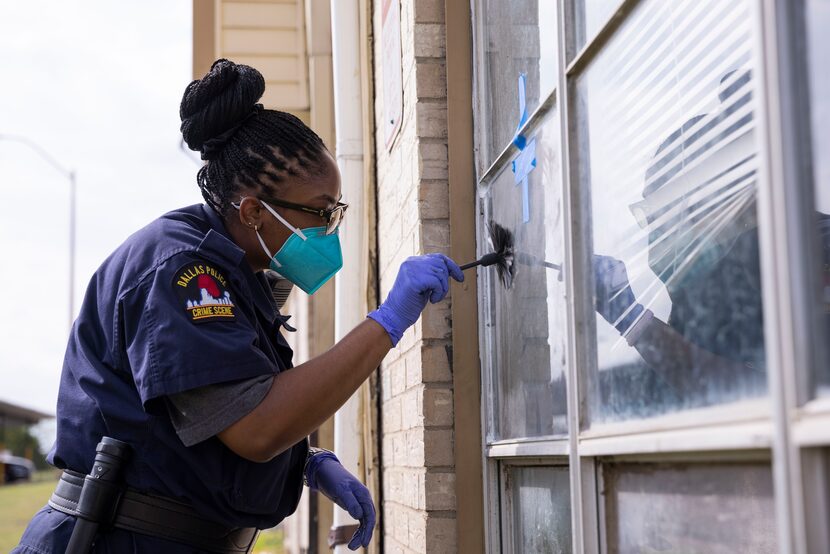 A Dallas Police crime scene investigator searches for prints outside of  Kayla and Daniel...