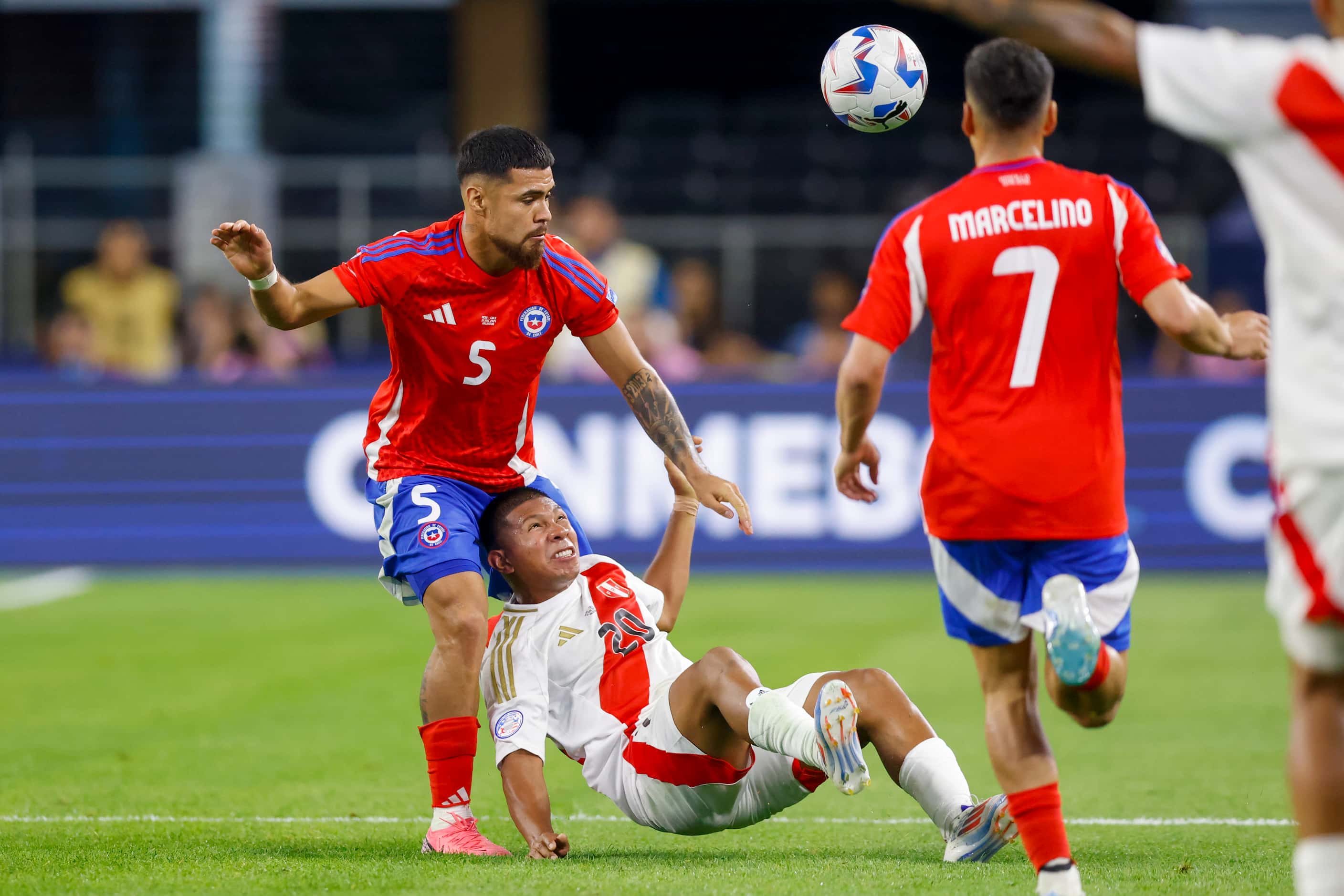 Peru forward Édison Flores (20) falls to the ground as he battles for the ball with Chile...