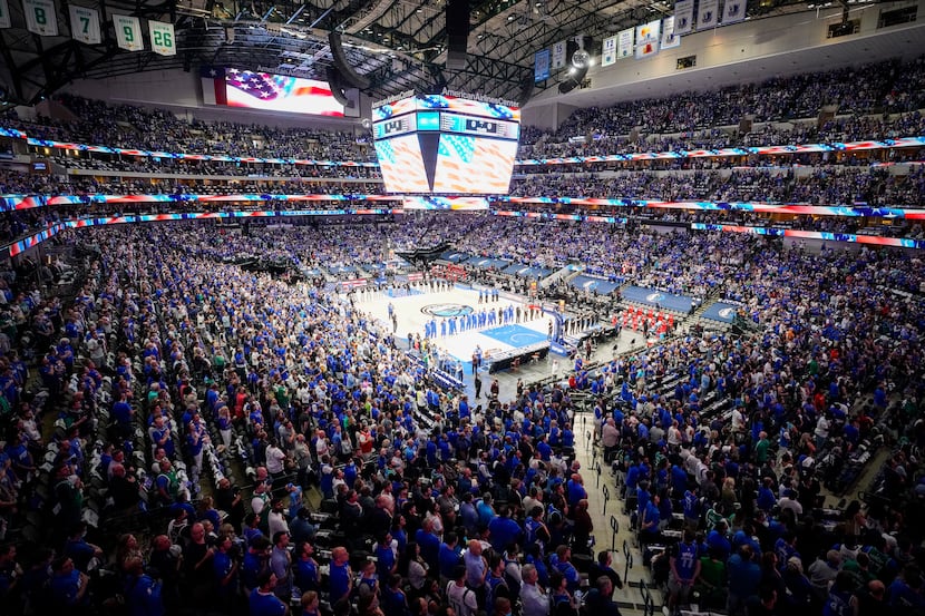 Dallas Mavericks players and fans stand for the national anthem before an NBA playoff...