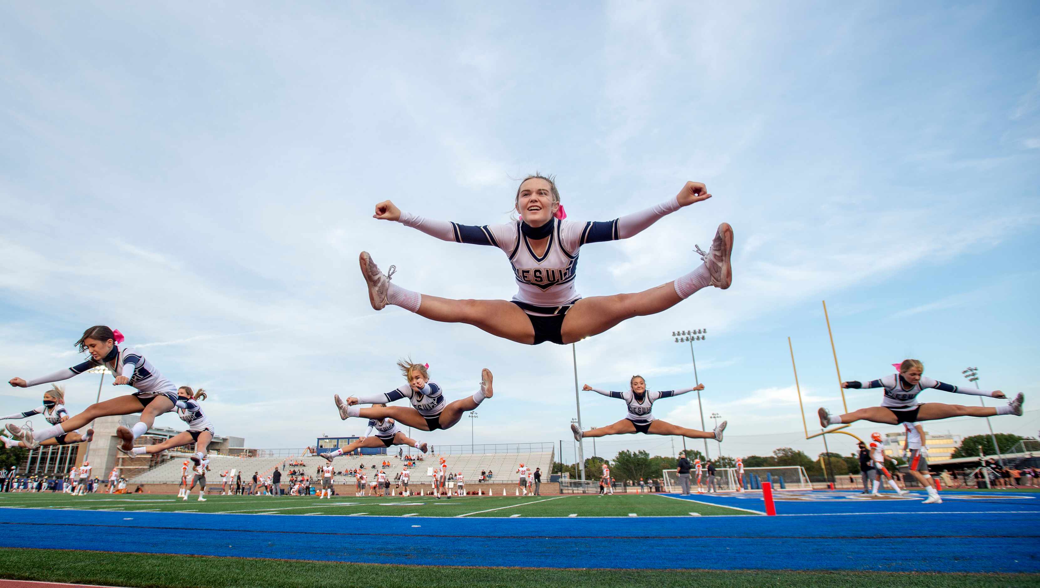 Emmy Smith, center, and other Jesuit cheerleaders practice jumps before a high school...