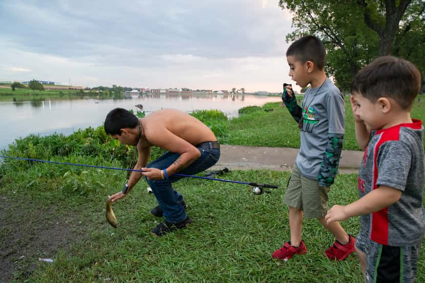 Terrance Hunt gets ready to throw a fish back as Milton Smith Ceren Mejía, 7, and Edrick...