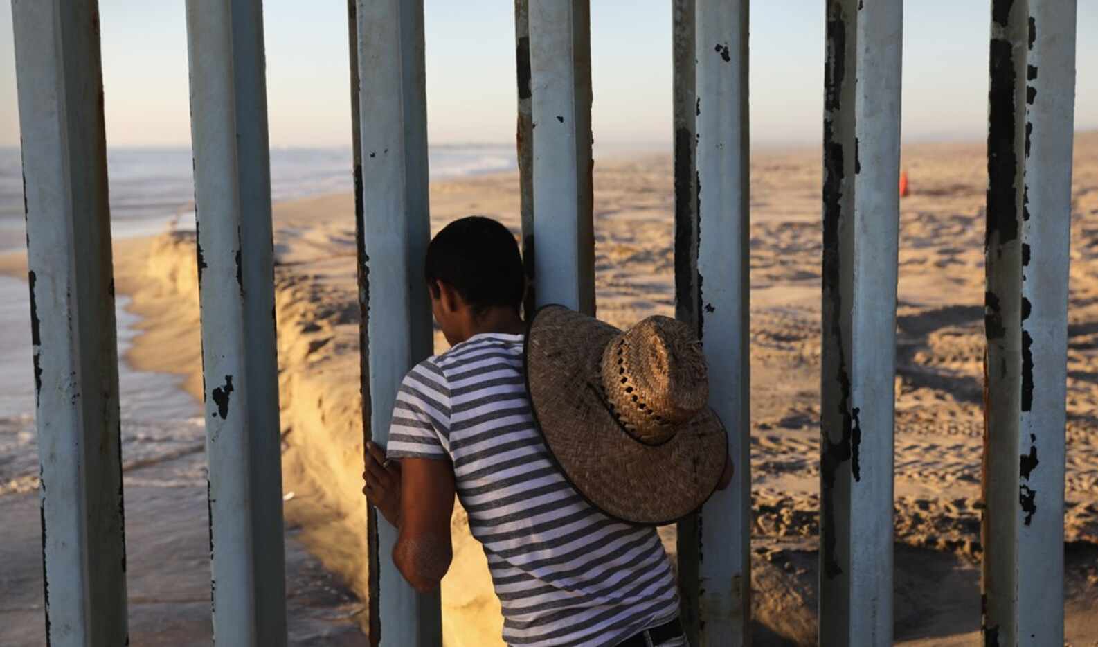 A man looks through the U.S.-Mexico border fence into the United States on September 25,...