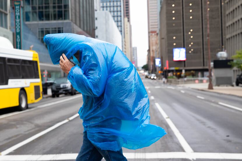 Ken Williams shields his face from the chilly wind as he walks in downtown Dallas on Friday,...