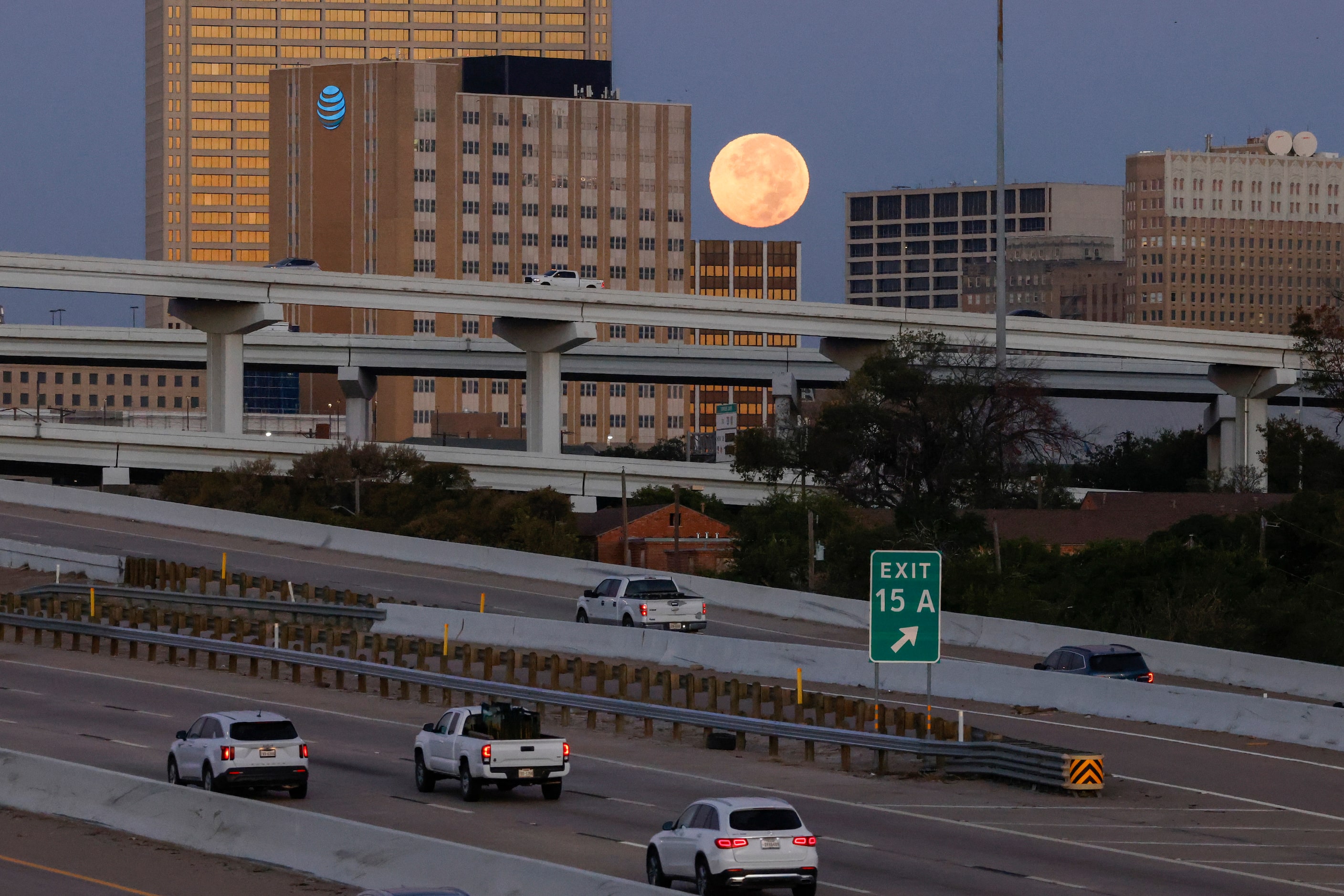 Traffic flows along Interstate 30 as a supermoon sets behind downtown Fort Worth, Thursday,...