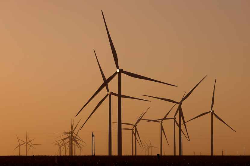 Dust from strong southerly winds partially obscure wind turbines spinning on the plains near...