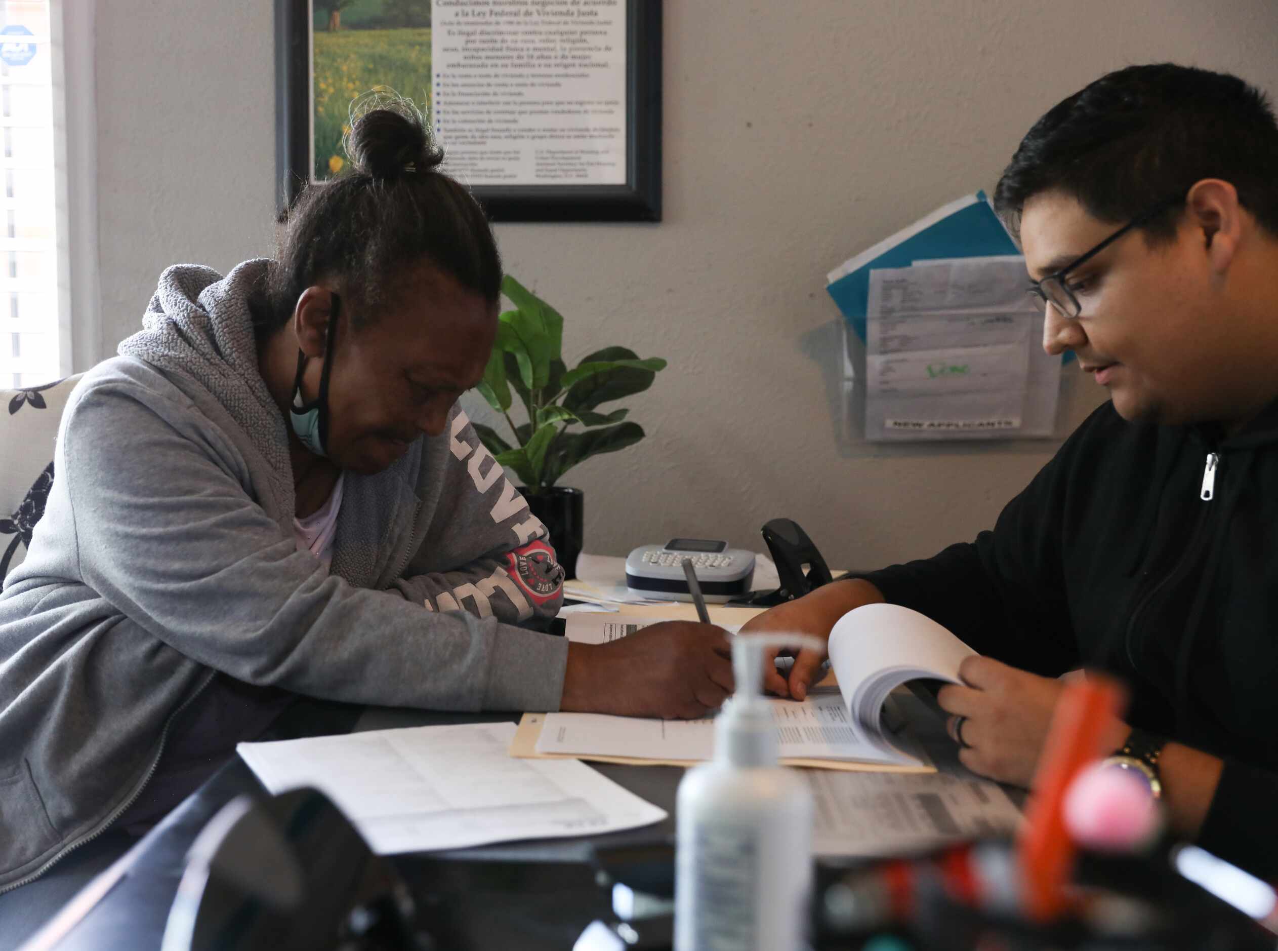 Assistant complex manager Sergio Duran (right) walks Patricia Freeman through the paperwork...