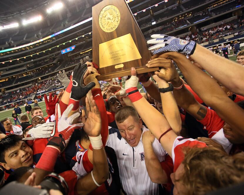 Allen head coach Tom Westerberg celebrates with his players after their 53-21 win during the...
