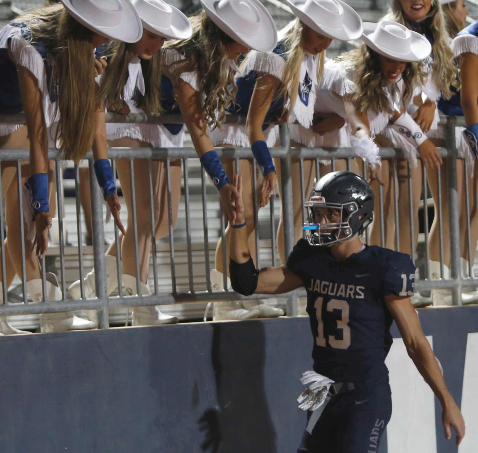 Flower Mound running back Pierce Hudgens (13) receives support from drill team members...