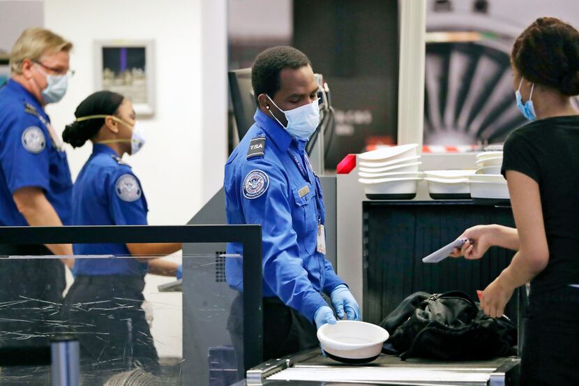 TSA officers wear protective masks at a security screening area at Seattle-Tacoma...
