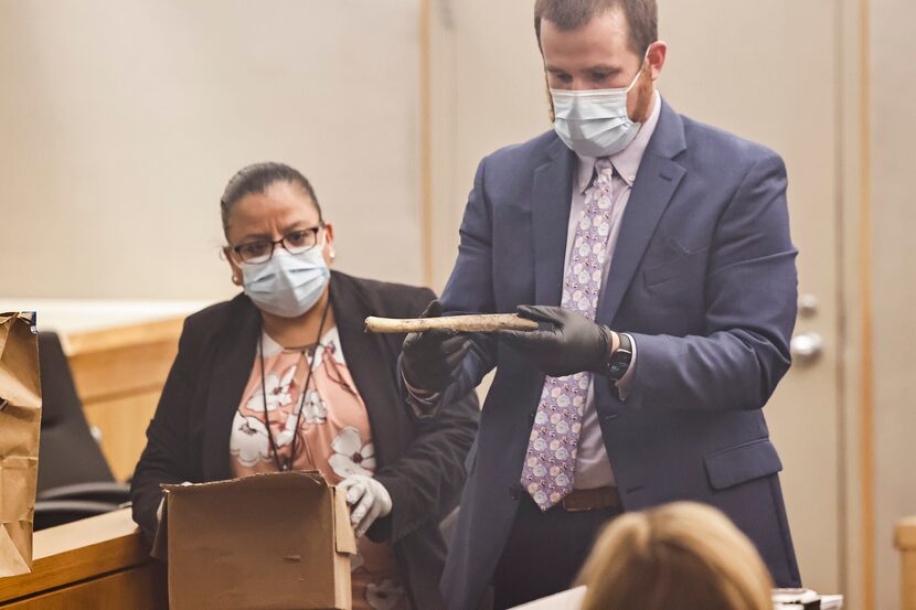 Prosecutor Zachery Brown (right) holds a bone taken from a box of evidence from Dallas...