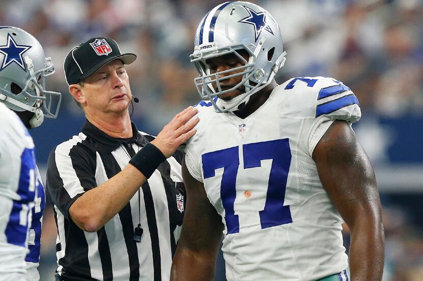 An official checks on Dallas Cowboys tackle Tyron Smith (77) after he sustained a stinger...