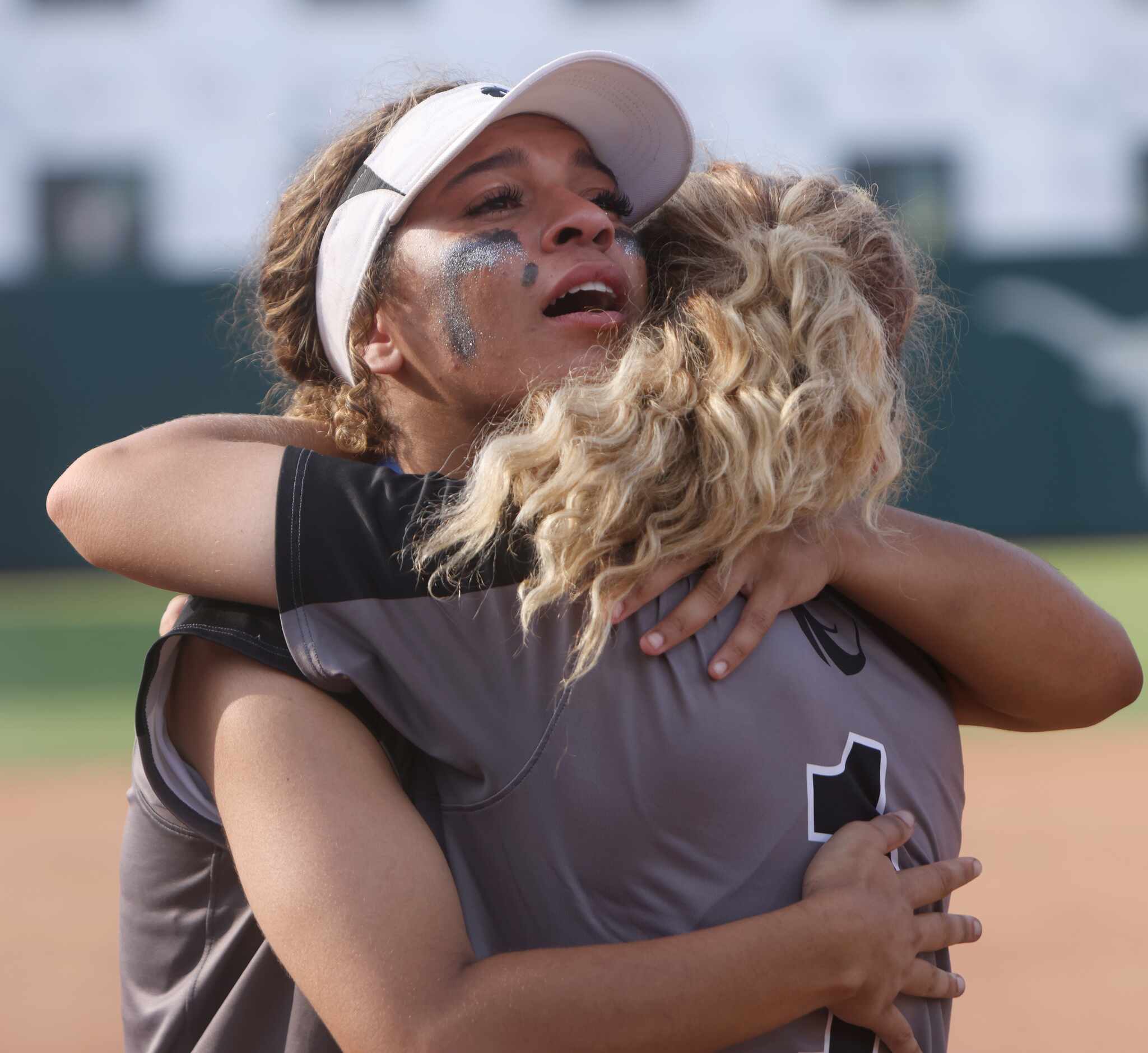 Denton Guyer center fielder Tehya Pitts (7, facing camera) shares a consoling hug with...
