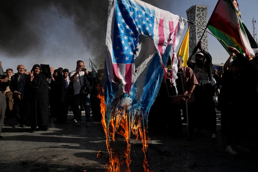 Demonstrators burn representations of the U.S. and Israeli flags in a rally commemorating...