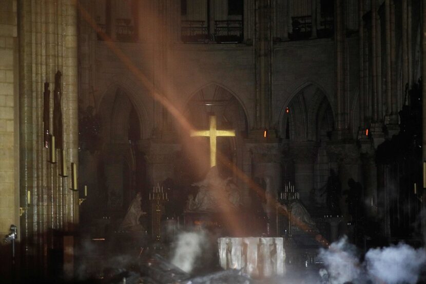 Smoke rises around the altar in front of the cross inside Notre Dame Cathedral as debris...