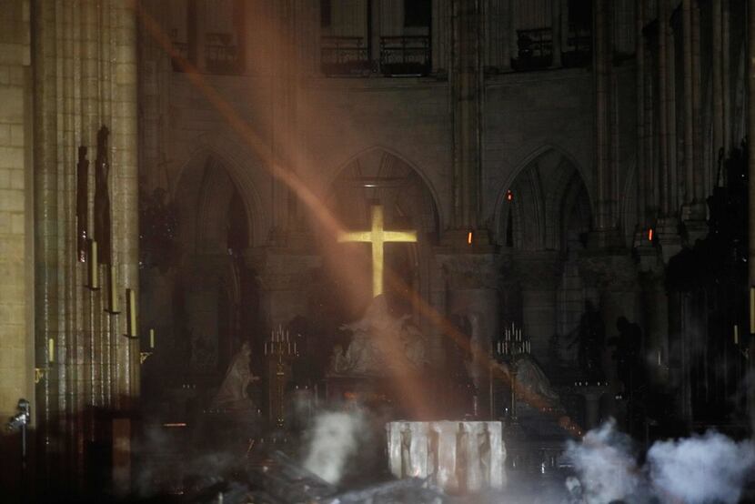 Smoke rises around the altar in front of the cross inside Notre Dame Cathedral as debris...