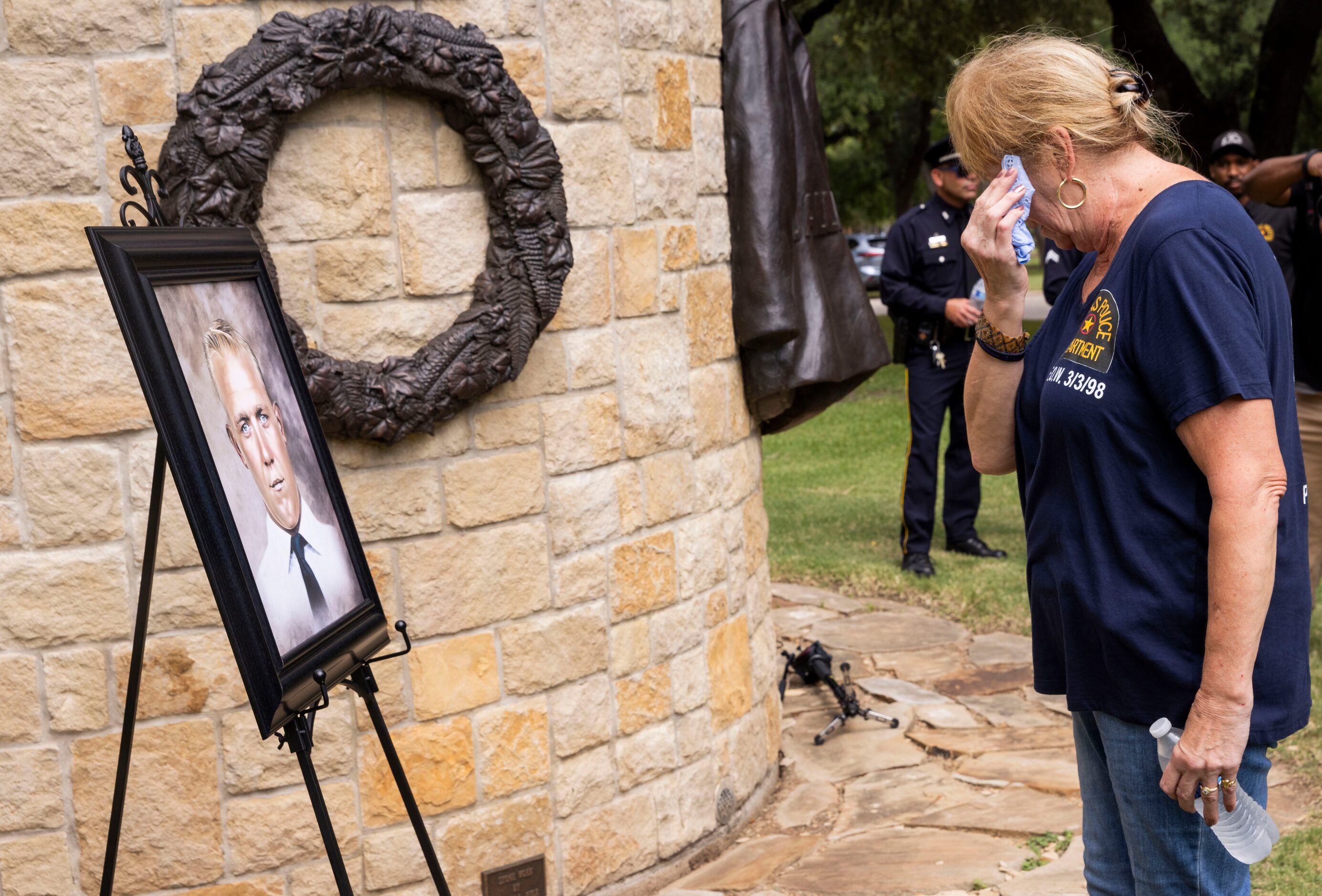 Kimberly Black wipes away tears while looking at a portrait of her father Sgt. Claude...