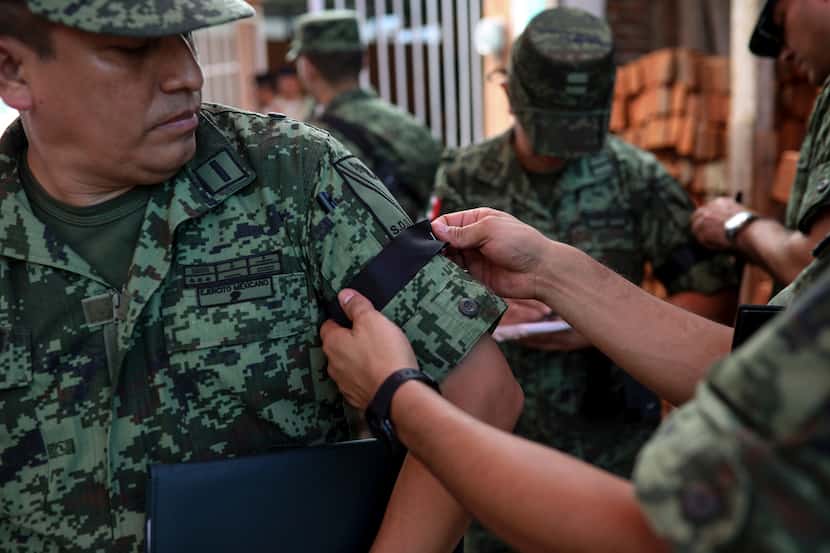 Un oficial del ejército mexicano recibe una cinta negra en la manga el sábado 19 de octubre...