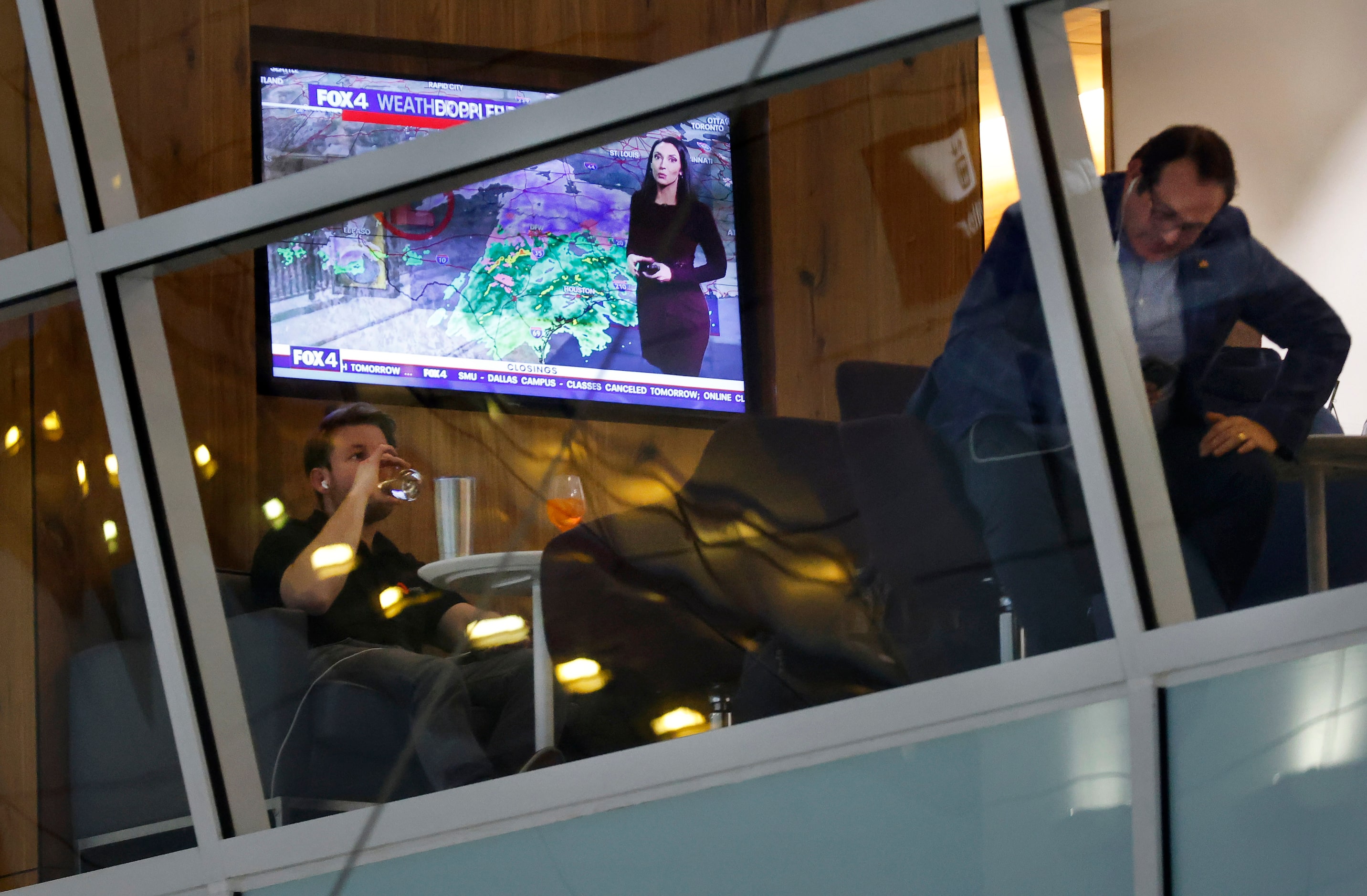 The local weather radar and report plays on a television as airline passengers relax in a...