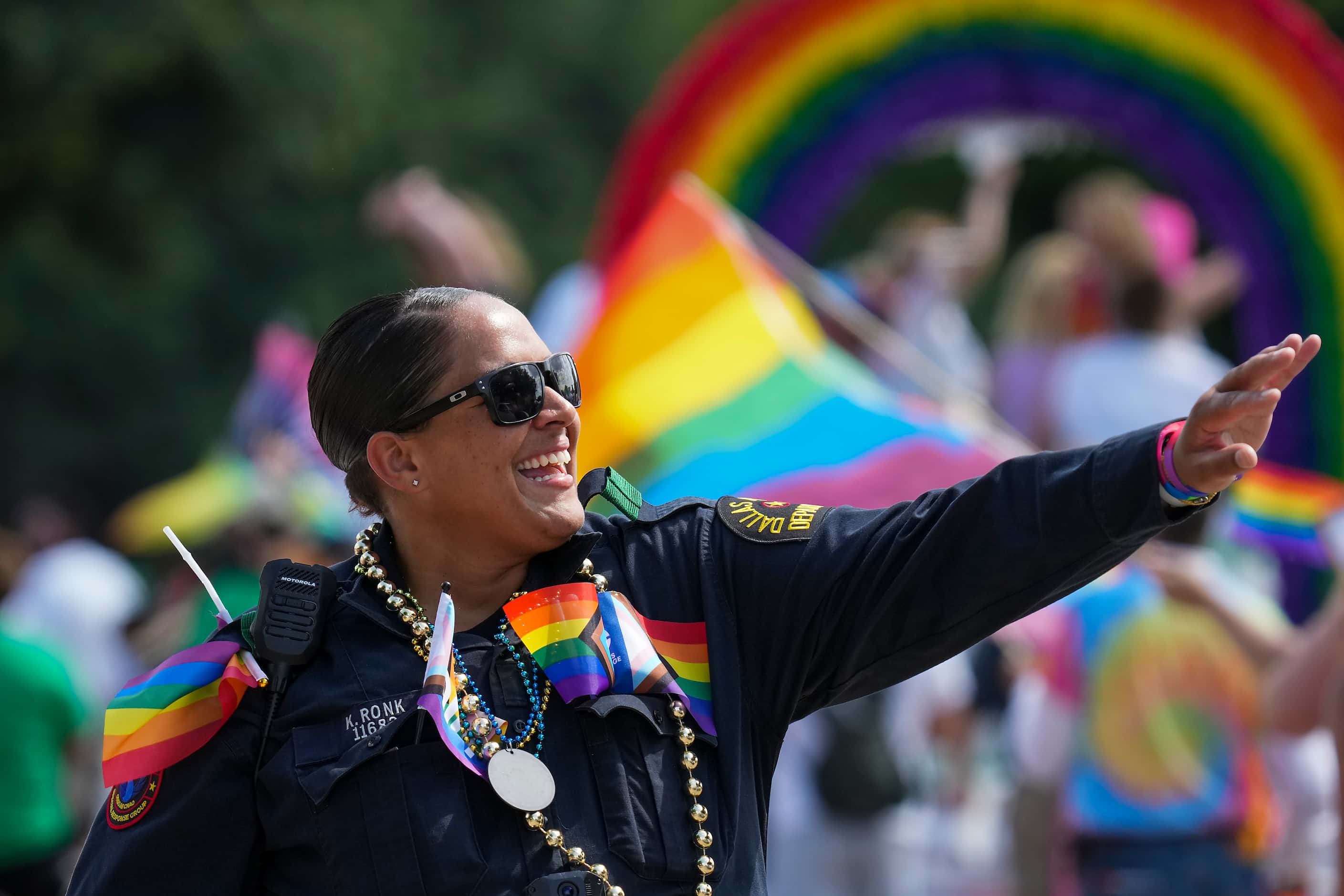 Dallas police officer K. Ronk waves to participants as they march through Fair Park during...