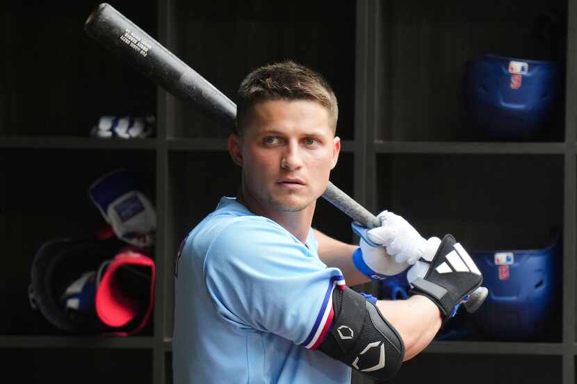 Texas Rangers designated hitter Corey Seager picks up a bat in the dugout during the seventh...