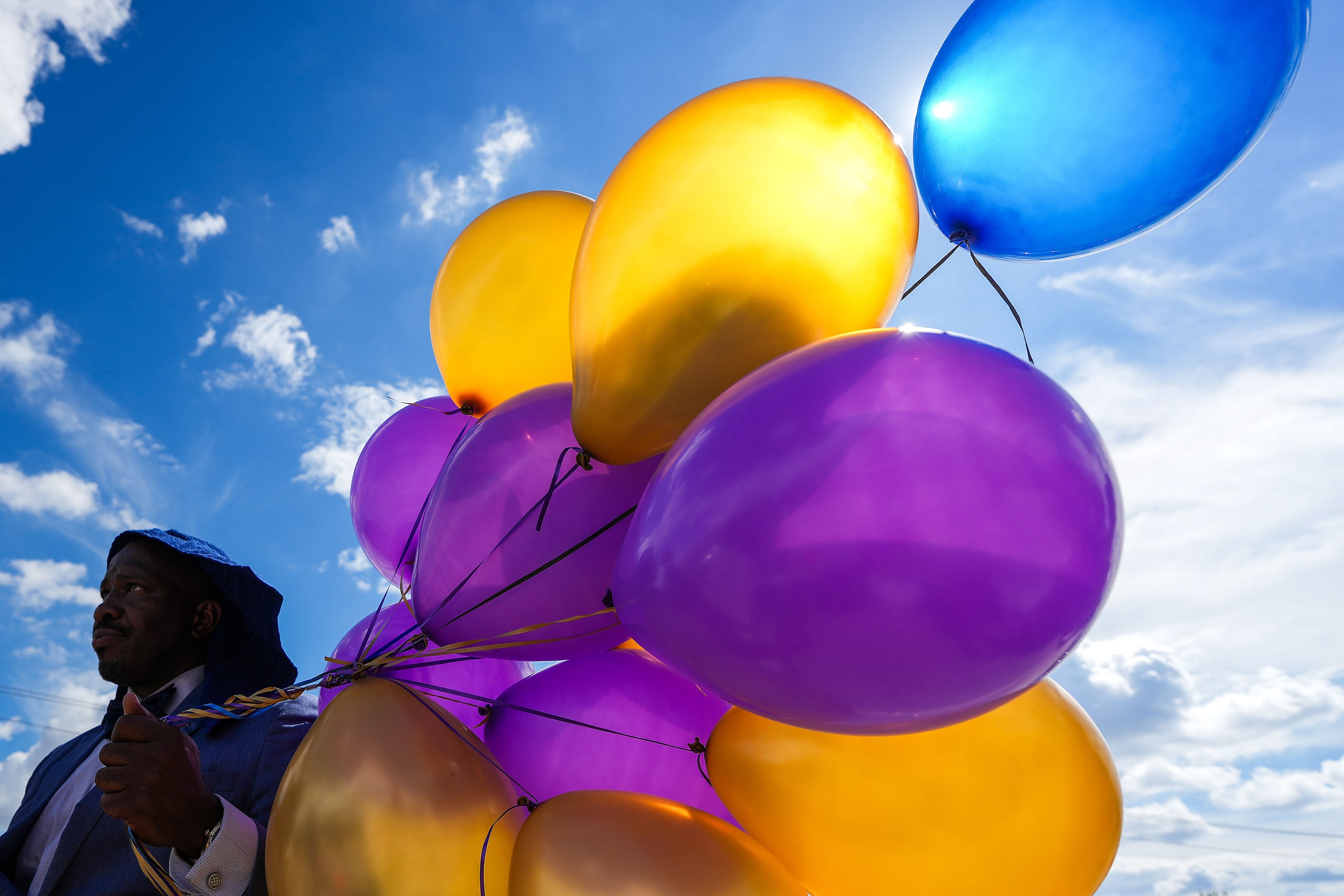 Keio Gamble carries balloons to place around a Dallas police patrol car serving as a...