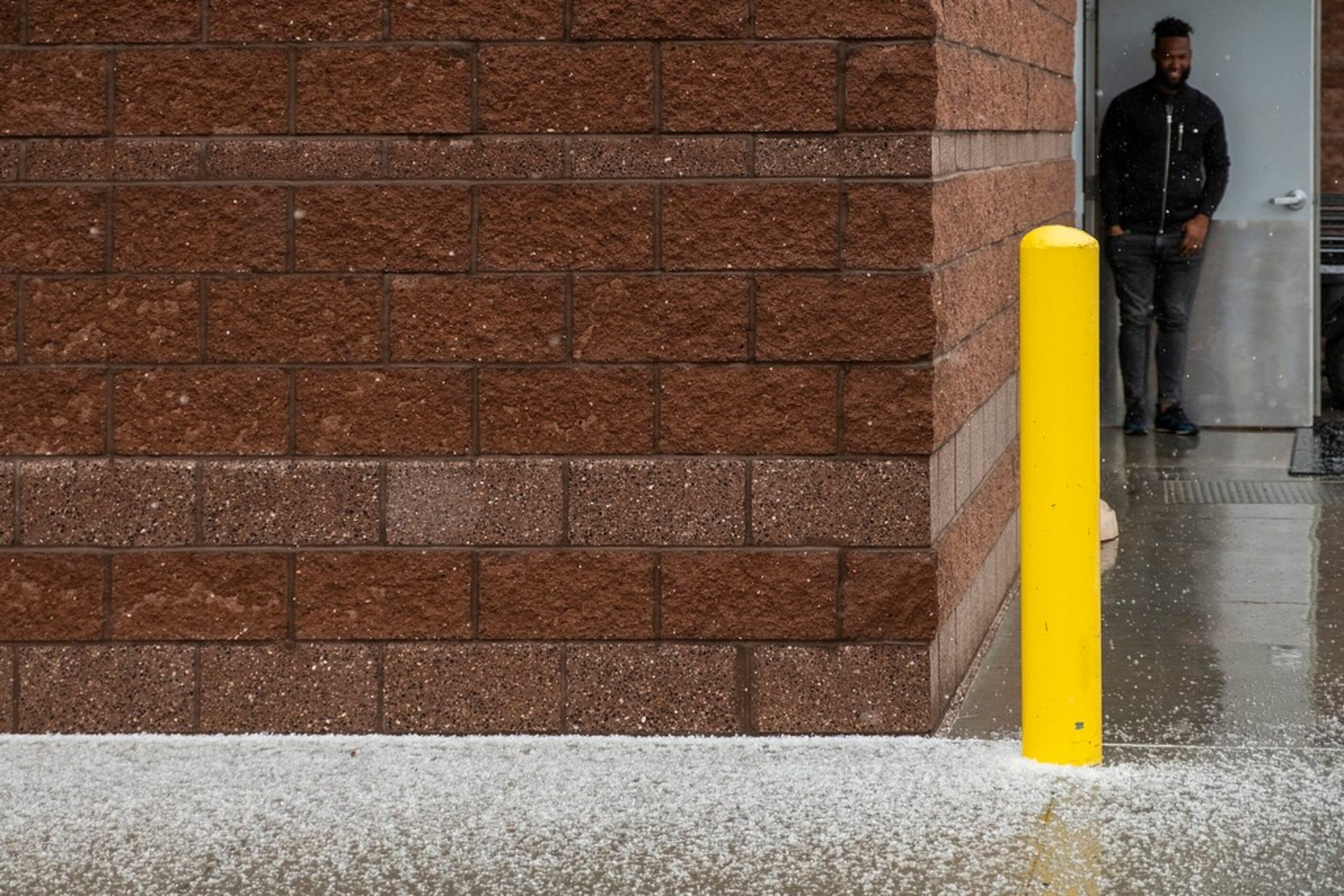 Texas Rangers outfielder Danny Santana watches snow pellets collect outside the clubhouse...