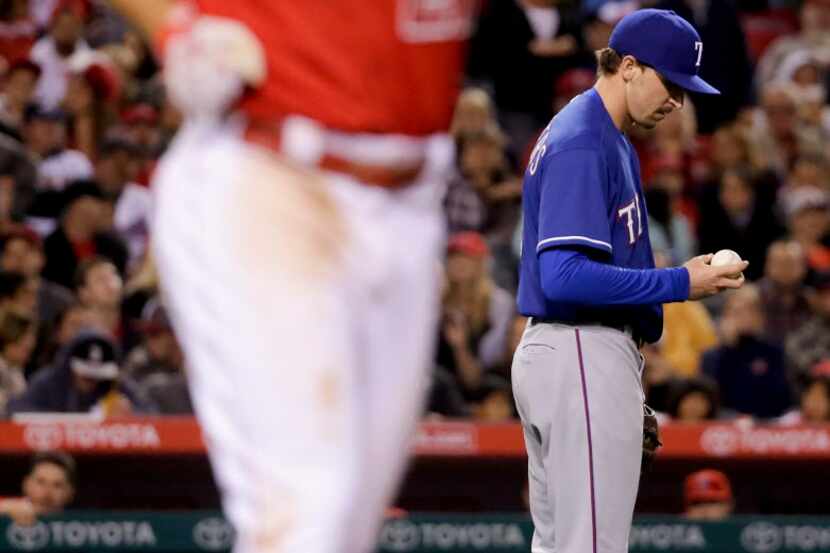 Texas Rangers starting pitcher Tanner Scheppers, right, looks at the ball after hitting Los...