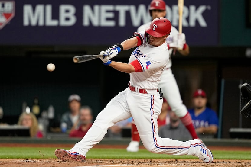 Texas Rangers' Corey Seager follows through on a run-scoring single in the third inning of a...