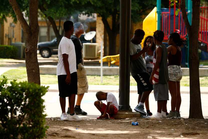 Children and teens gather near the scene of a shooting that left two bullets in a...