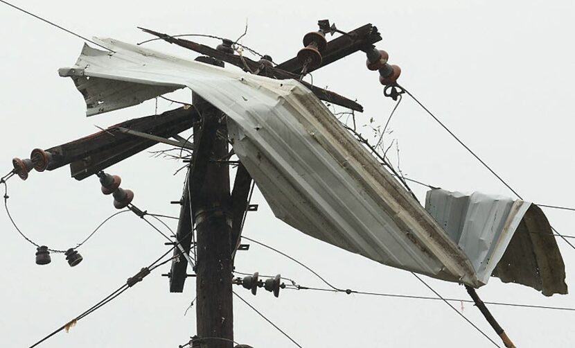 A slab of corrugated metal siding was left tangled in the lines atop a utility pole in Van...