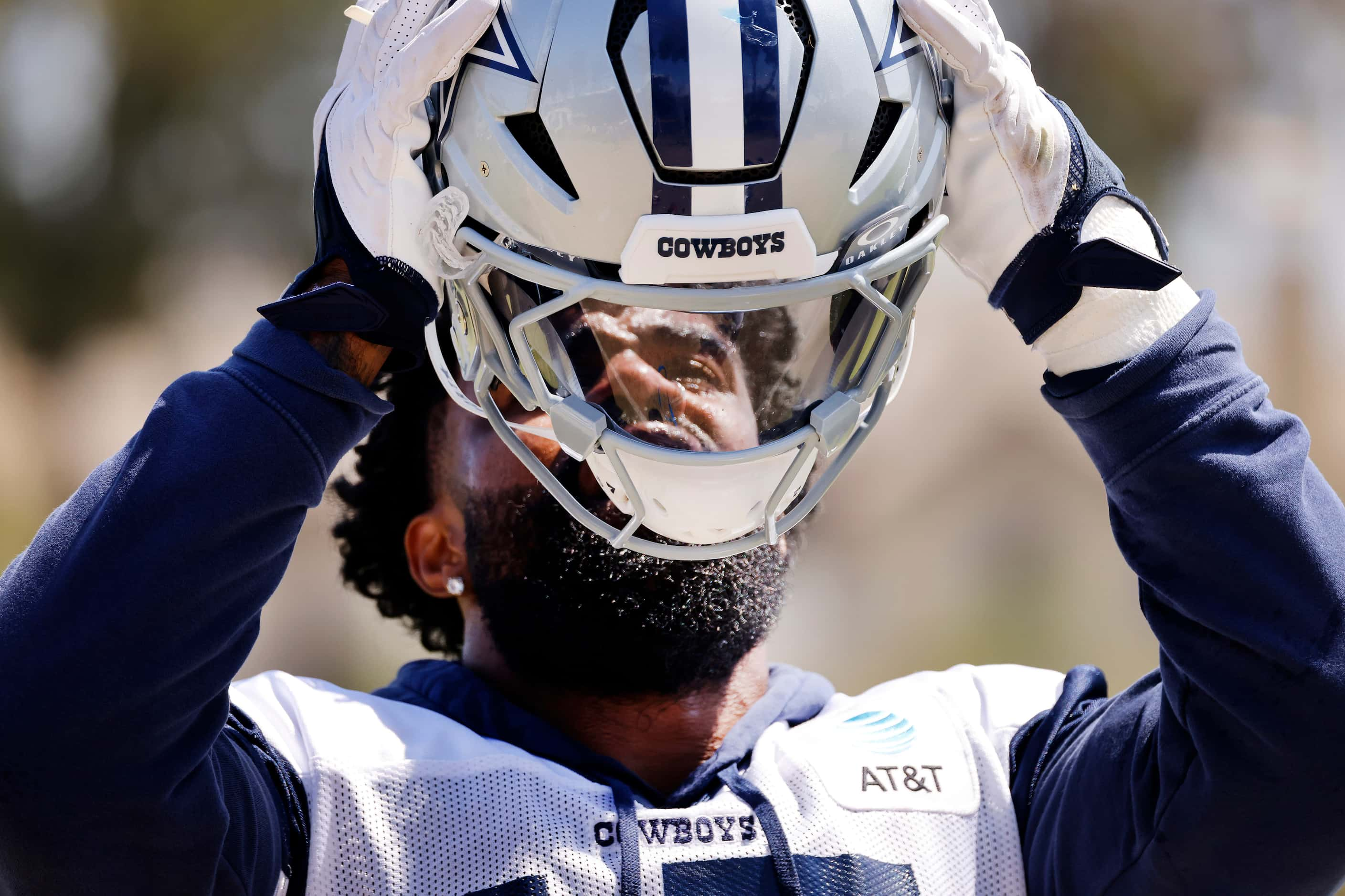 Dallas Cowboys running back Ezekiel Elliott (15) puts on his helmet before running drills...