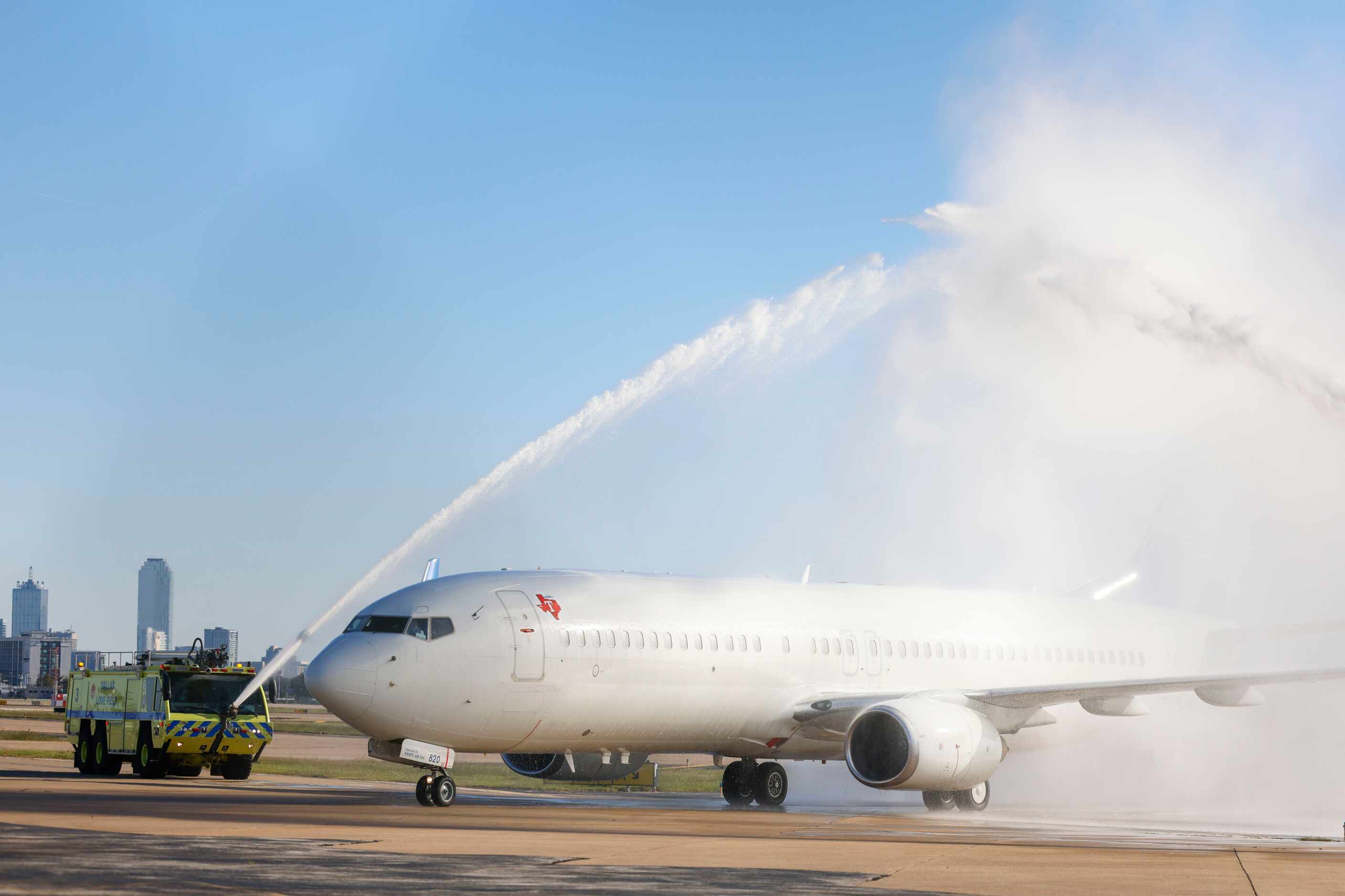Texas Rangers players arrive at Dallas Love Field as rescue trucks doused water over the...