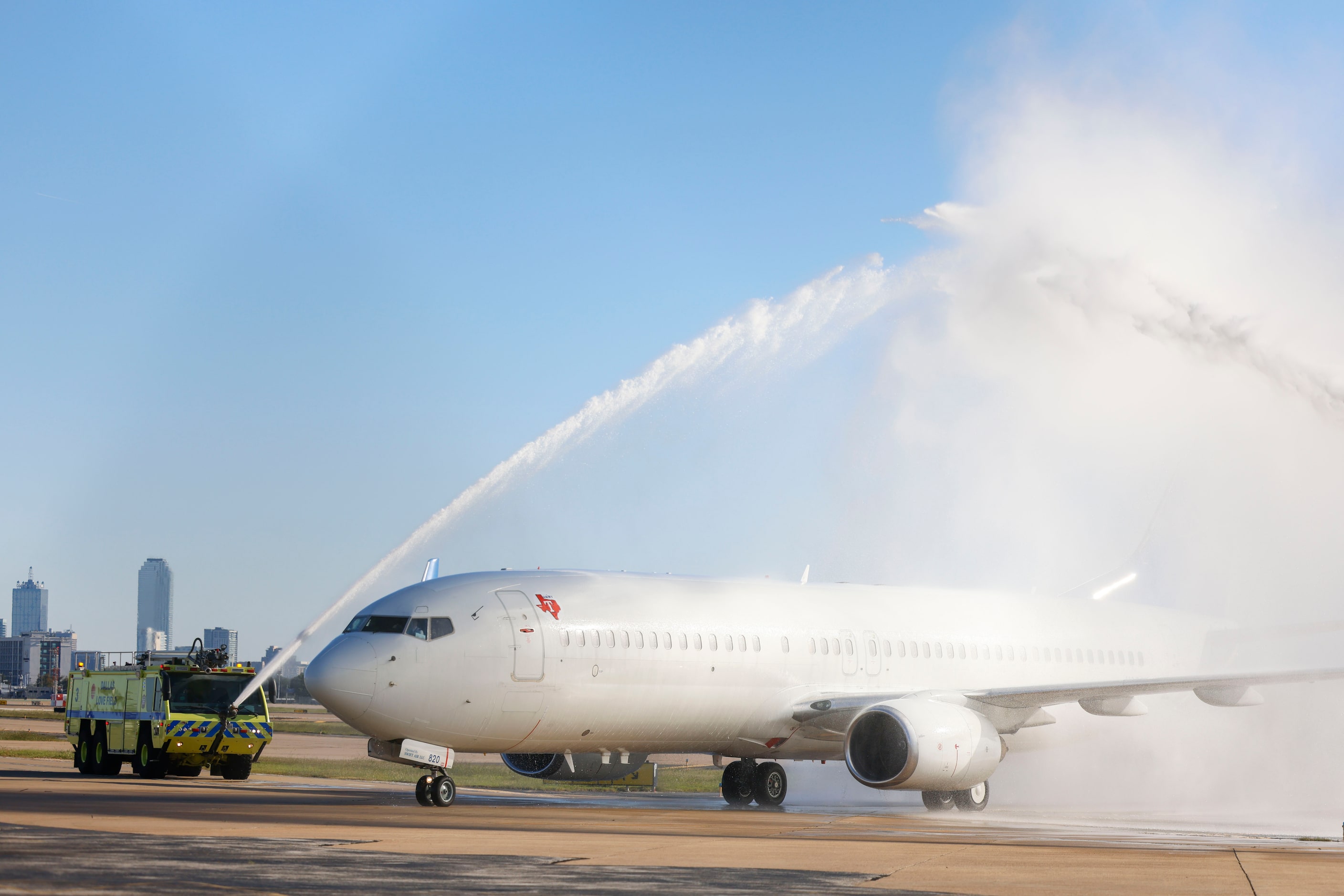 Texas Rangers players arrive at Dallas Love Field as rescue trucks doused water over the...