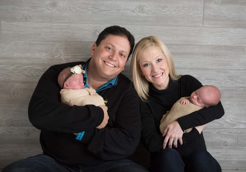 Mark and Amber Freed hold one-month-old twins Riley, in Mark's arms, and Maxwell, held by...
