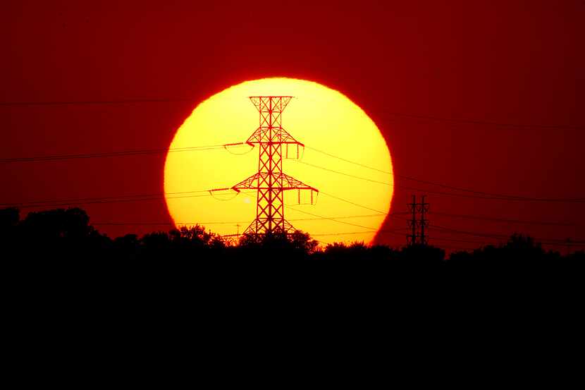 The sun sets behind power lines near Mountain Creek Lake as a plane taking off from DFW...