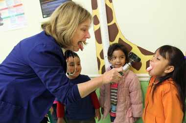 La enfermera Martha Strong pide a Maryannie Flores, de 7 años, abrir la boca para examinarla...