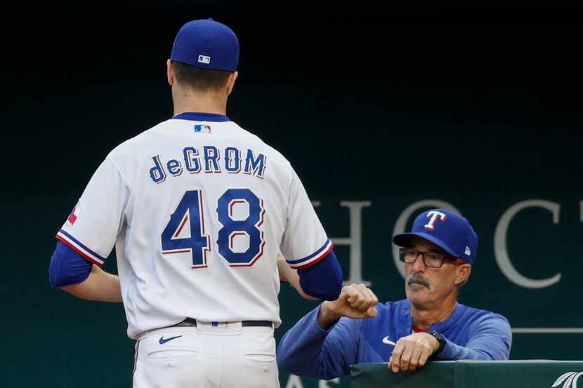 Texas Rangers starting pitcher Jacob deGrom (48) fist bumps pitching coach Mike Maddux (31)...